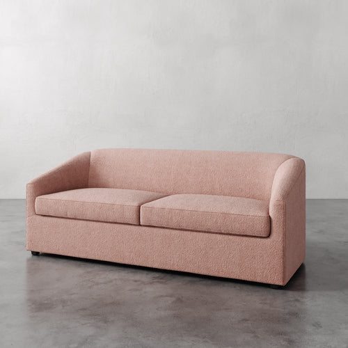 Lemieux et Cie Arvelle Queen Sleeper in blush, two-cushion sofa with rounded arms, shown on polished concrete floor against white walls.
