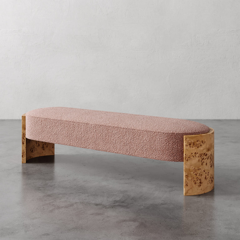 Lemieux et Cie Benoit Custom Upholstered Bench in blush bouclé with curved Maple burl legs, on concrete floor against textured plaster walls