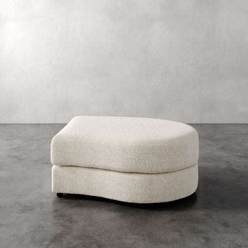 Lemieux Et Cie Rulmann Right Ottoman Beige ottoman on a gray floor with a plain white wall background