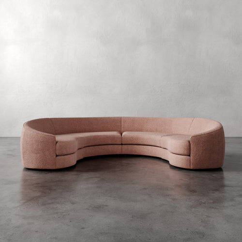 Lemieux Et Cie Rulmann 4-Piece Sectional Curved pink sofa on a gray floor with a neutral background