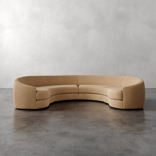 Lemieux Et Cie Rulmann 4-Piece Sectional  Beige curved sofa on a gray floor with a plain wall background
