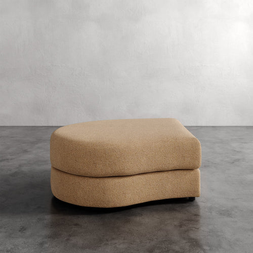 Lemieux Et Cie Rulmann Left Ottoman Beige ottoman on a gray floor with a plain white wall background