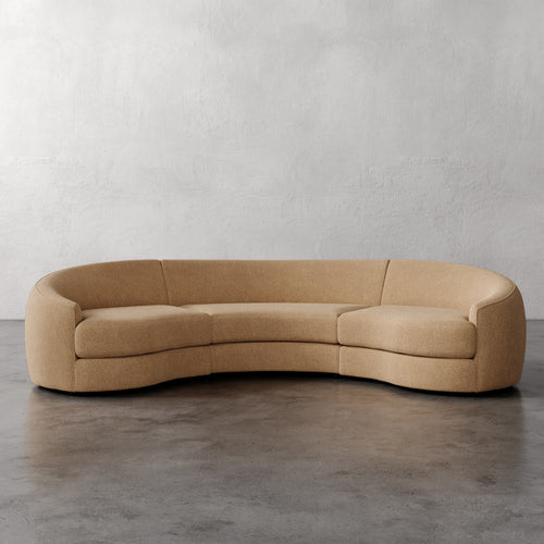 Lemieux Et Cie Rulmann Rulmann 3-Piece Sectional Beige curved sofa on a gray floor with a plain wall background