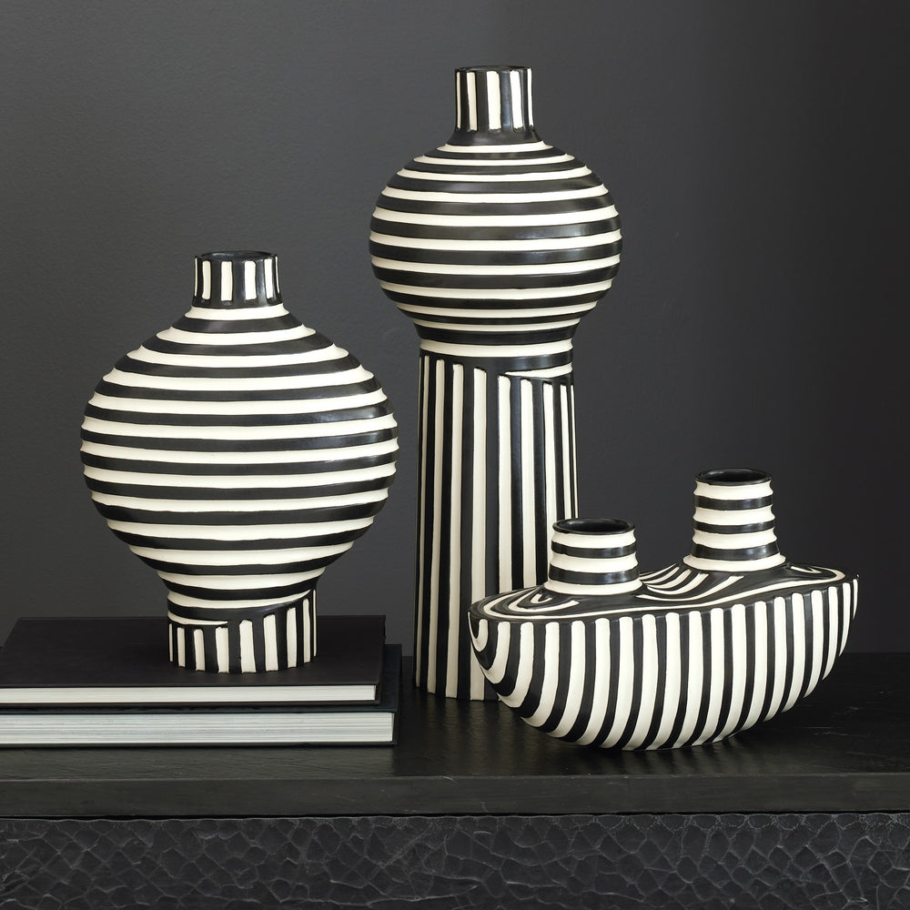 Lemieux et Cie ceramic vases with hand-painted black and white striped patterns, sculptural forms grouped on dark wood surface against charcoal wall.