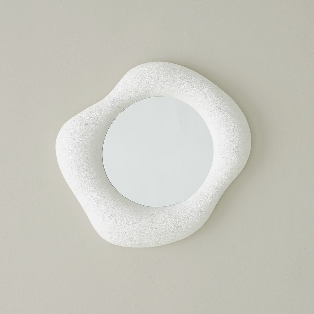 Lemieux et Cie hand-sculpted mirror with organic asymmetrical white frame, shown on neutral plaster wall in soft light.