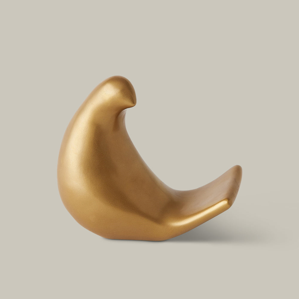 Lemieux et Cie bird object in warm gold finish, sculptural dove form with curved silhouette, shown on neutral studio backdrop.