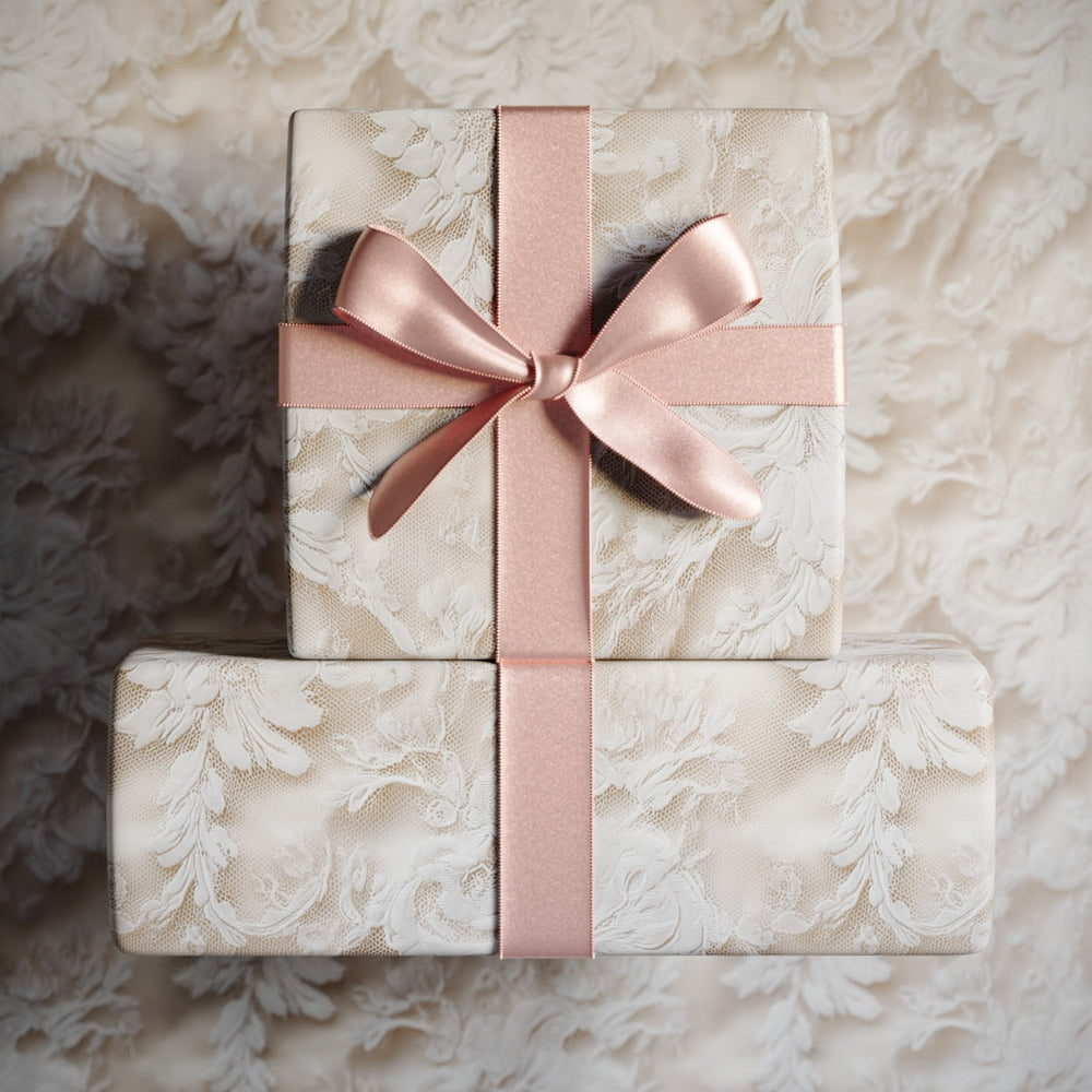 Lemieux et Cie Chantilly Lace Gift Wrapping Paper with blush ribbon, two wrapped boxes in soft blue and ivory floral pattern on neutral textured surface.