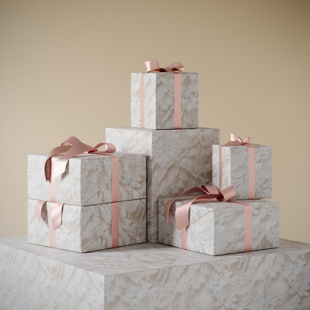 Lemieux et Cie Chantilly Lace Gift Wrapping Paper in soft blue and ivory, stacked wrapped boxes with blush ribbon on neutral backdrop.