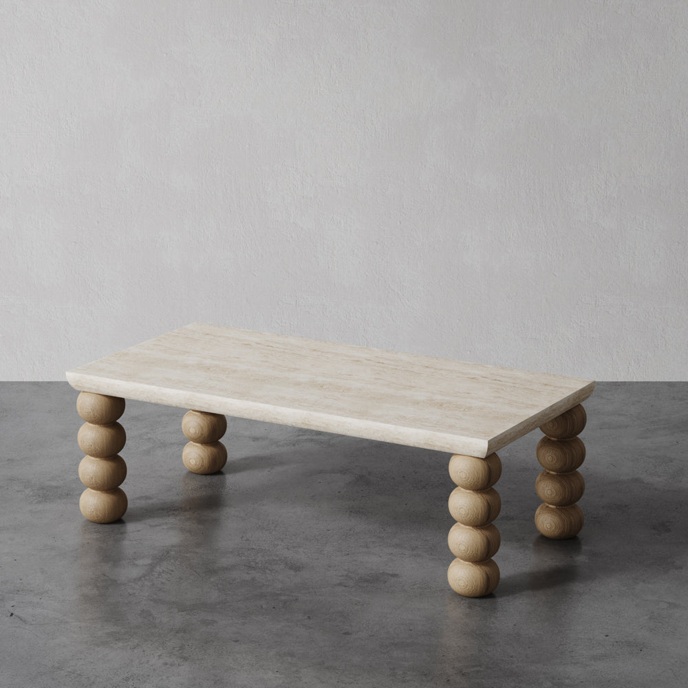 Lemieux et Cie Chloé Console Table in travertine with hand-turned oak sphere legs, sculptural low table on concrete flooring against neutral walls.