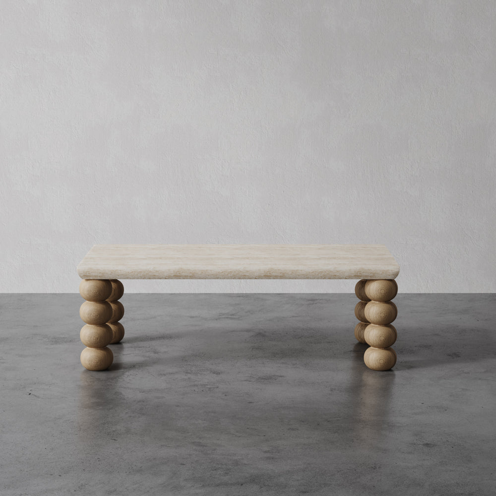 Lemieux et Cie Chloé Console Table in travertine and oak, low table with hand-turned spherical legs, shown on concrete floor against neutral walls.