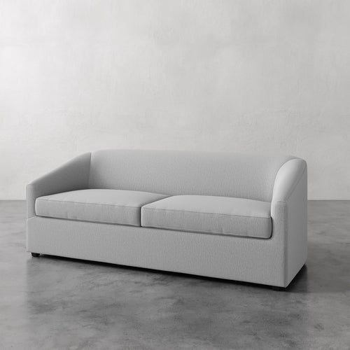 Lemieux et Cie Arvelle Queen Sleeper in pale gray, two-cushion sofa with rounded arms, shown on polished concrete floor against white plaster walls.