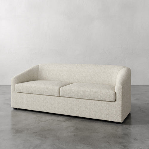 Lemieux et Cie Arvelle Queen Sleeper in cream, low-profile sofa with slim squared arms, shown on concrete floor against neutral plaster walls.