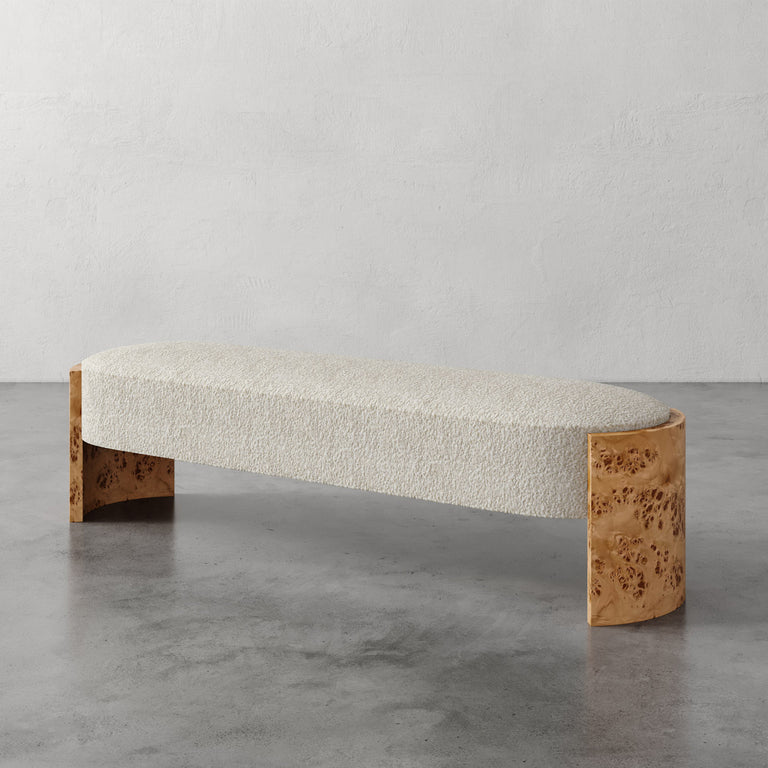 Lemieux et Cie Benoit Custom Upholstered Bench in ivory bouclé with curved Maple burl legs, shown on polished concrete floor against neutral plaster wall.