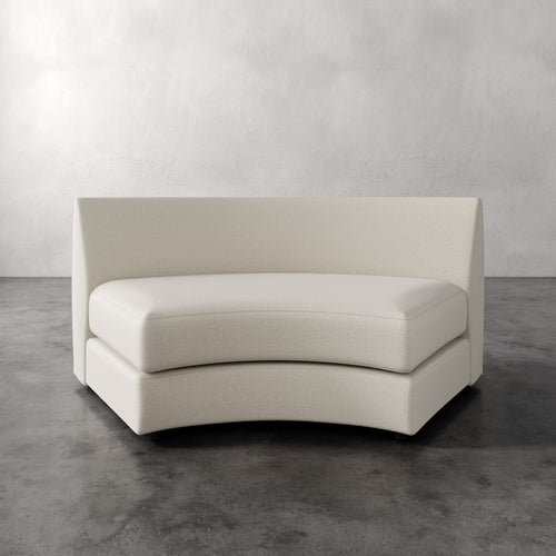 Lemieux Et Cie Rulmann Wedge White curved sofa on a gray floor with a light gray wall background