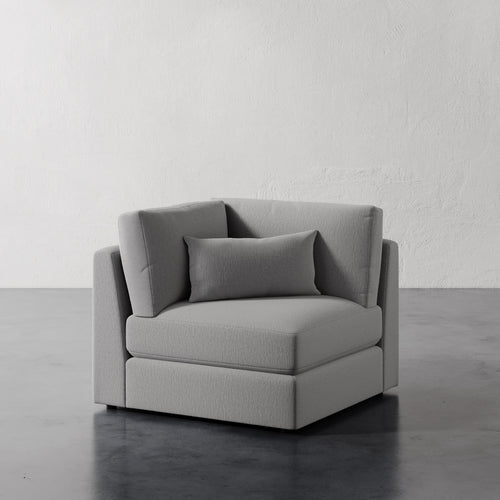 Lemieux Et Cie Lacroix Corner Chair Grey velvet chair against a plain white wall.