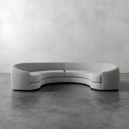 Lemieux Et Cie Rulmann 4-Piece Sectional Modern curved sofa in a minimalistic setting with a plain wall and concrete floor.