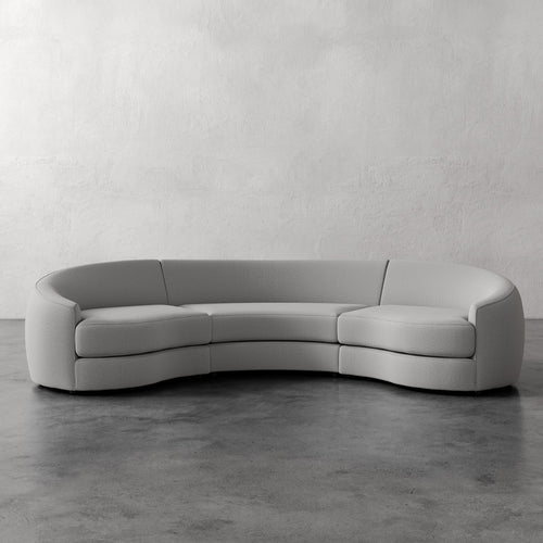 Lemieux Et Cie Rulmann Rulmann 3-Piece Sectional Gray curved sectional sofa on a concrete floor with a white wall background