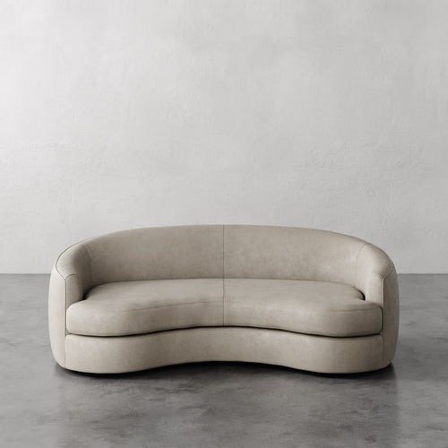 Lemieux et Cie Light Grey Rulmann leather sofa on a gray floor with a plain white wall background