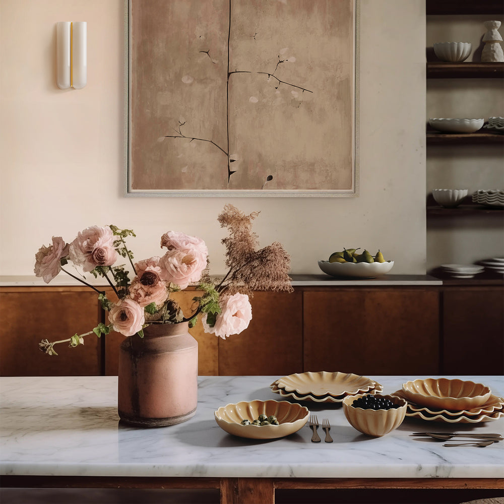 Lemieux et Cie Dhalia Stoneware dinnerware set in camel with reactive glaze, arranged on marble table in warm dining room with neutral walls and shelving.