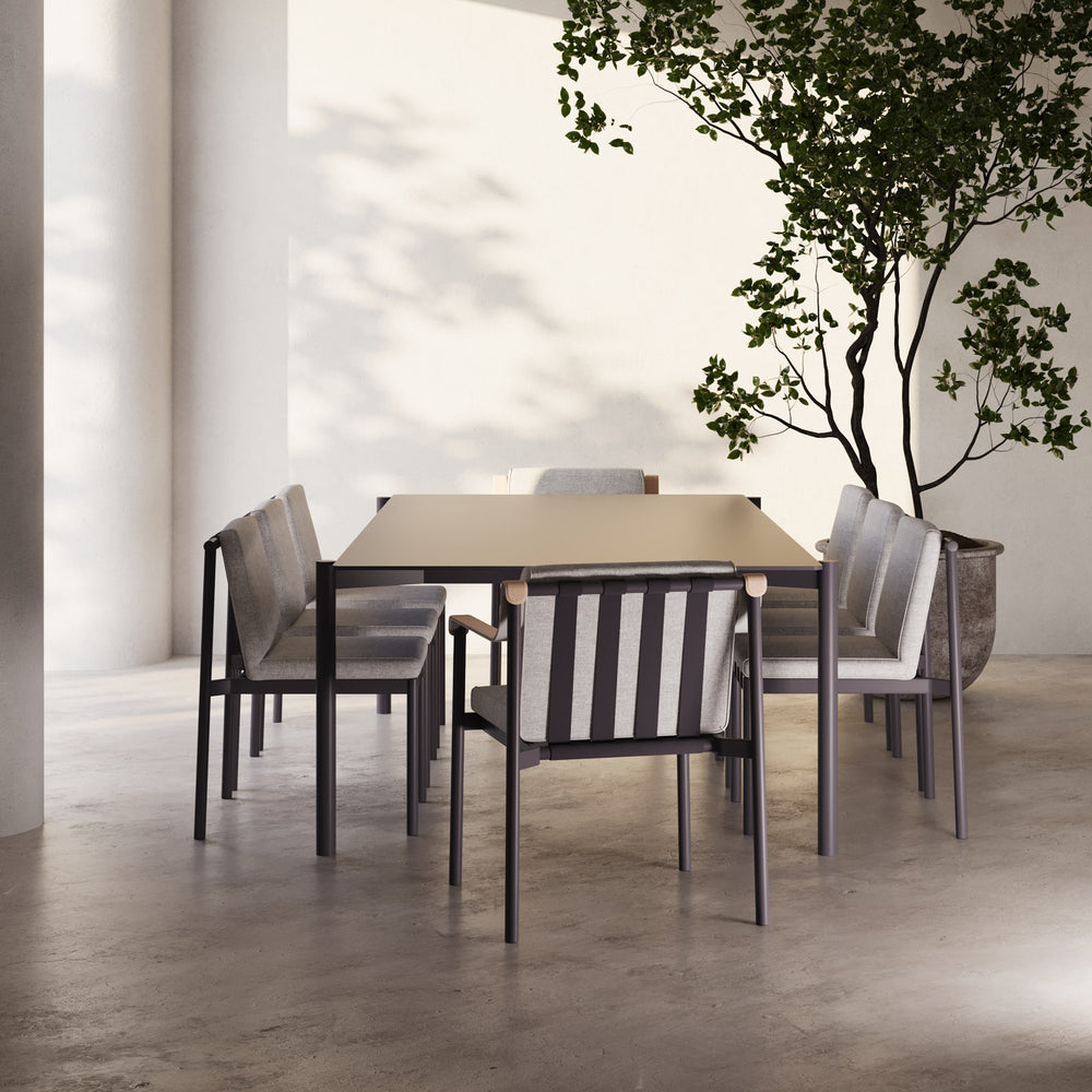 Lemieux et Cie Hudson 84" Rectangular Dining Table with dark frame and light top, shown with upholstered dining chairs in a high-ceilinged room with concrete floors and white plaster walls.