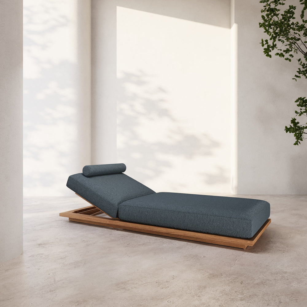 Lemieux et Cie S2 Teak Chaise Lounge in charcoal with solid teak base, outdoor daybed with adjustable bolster pillow on stone floor in soft daylight.