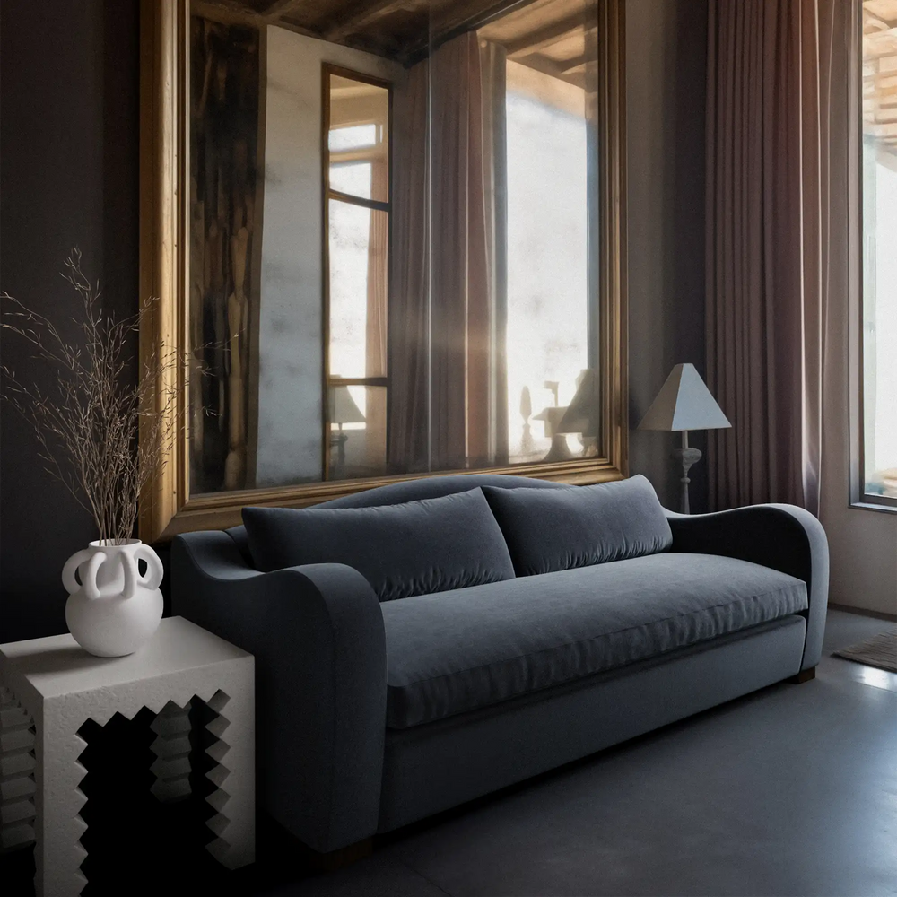 Lemieux et Cie Elodie Sofa with bench seat in charcoal, curved-arm sofa in a moody sitting room with dark floors and tall curtained windows.