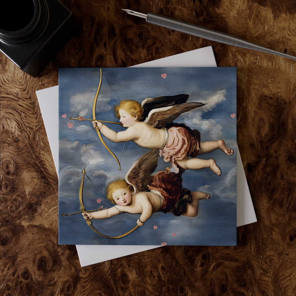 Lemieux et Cie Renaissance Cupid Greeting Card Set featuring two winged cherubs on linen paper, styled on burl wood desk with pen and envelope.
