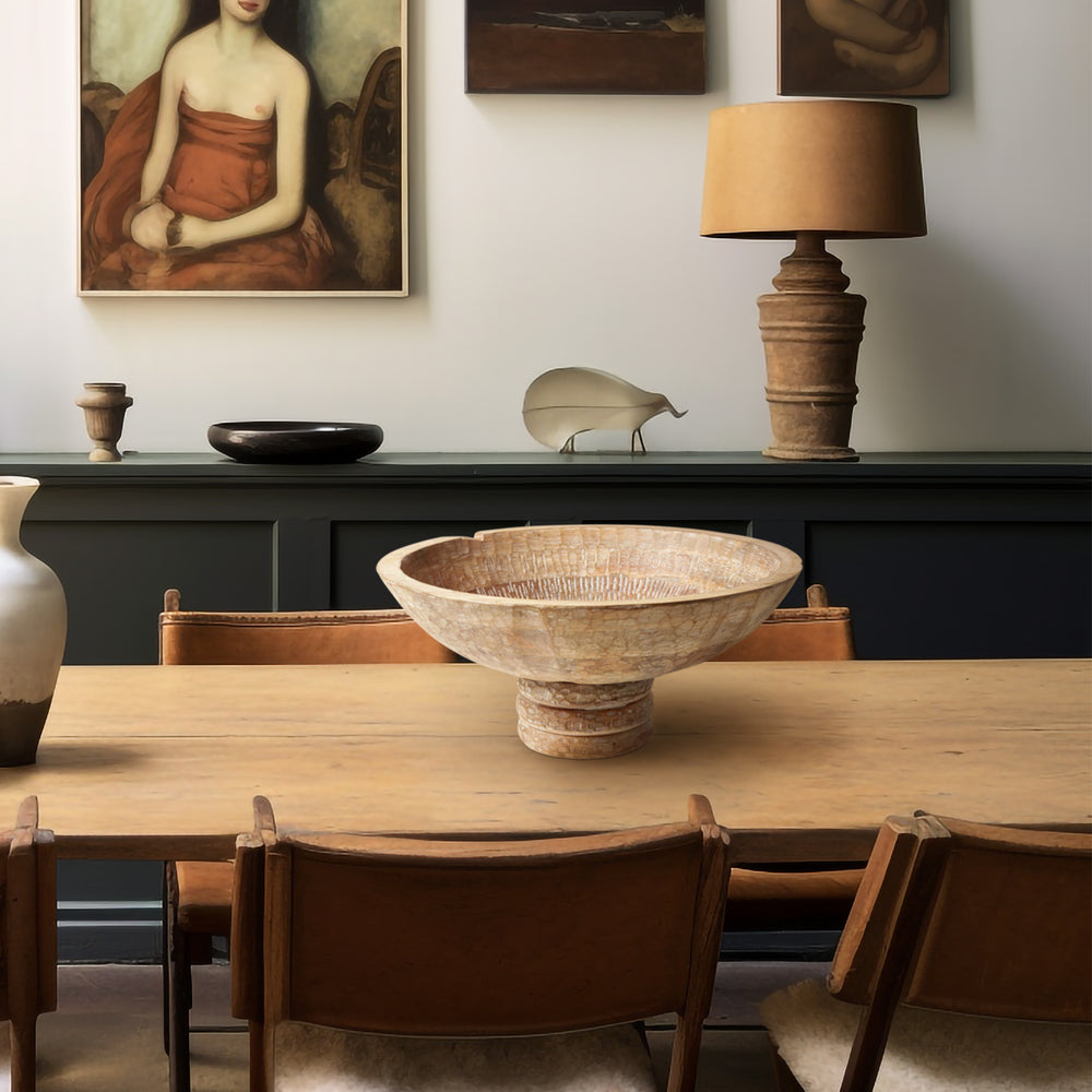 Lemieux et Cie Giraud Bowl, hand-carved footed bowl with textured surface, centered on wood dining table in a room with white walls and framed art.