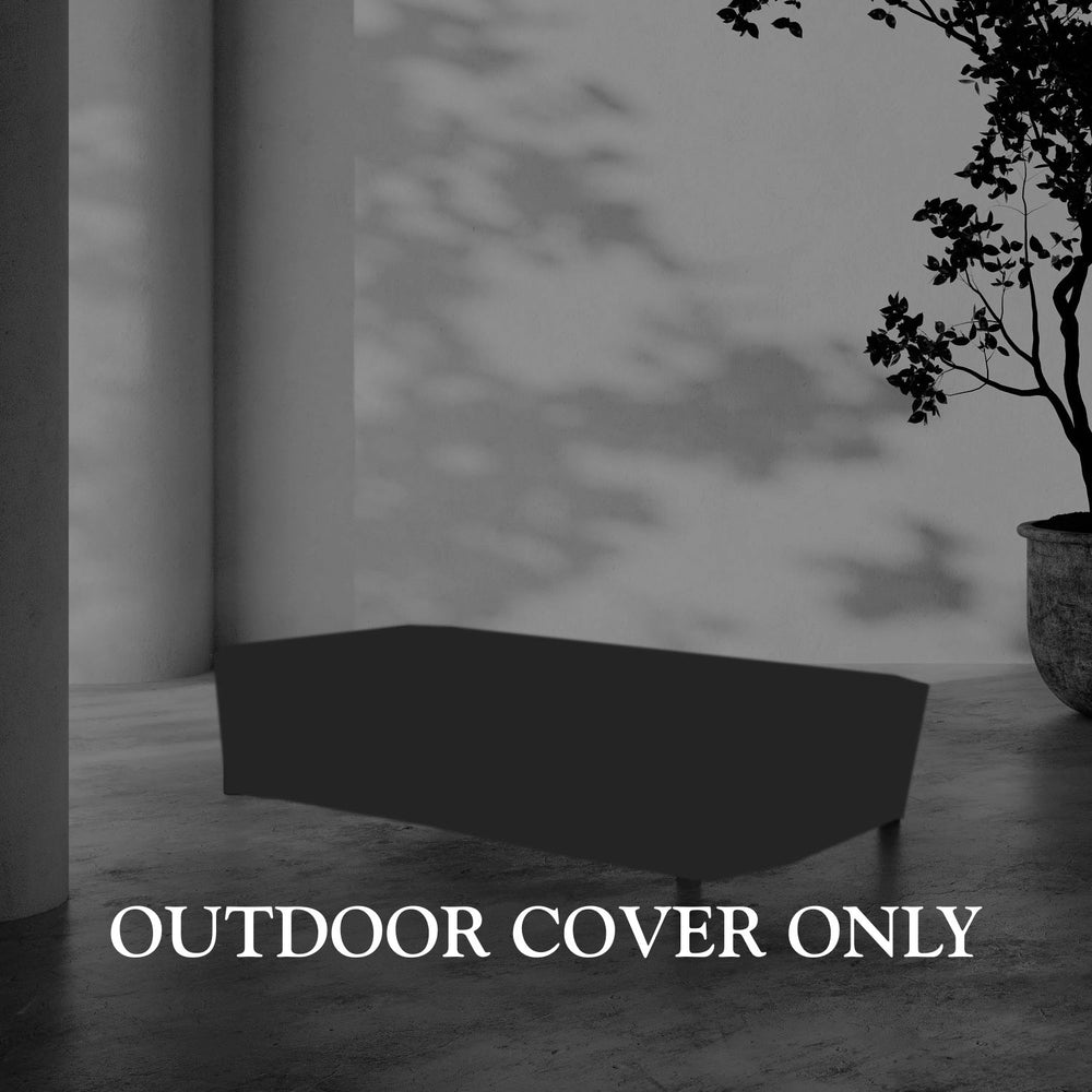 Lemieux et Cie Hudson Rectangular Coffee Table Outdoor Cover, low-profile fitted cover on stone flooring beside a column with dappled shadow and potted tree.