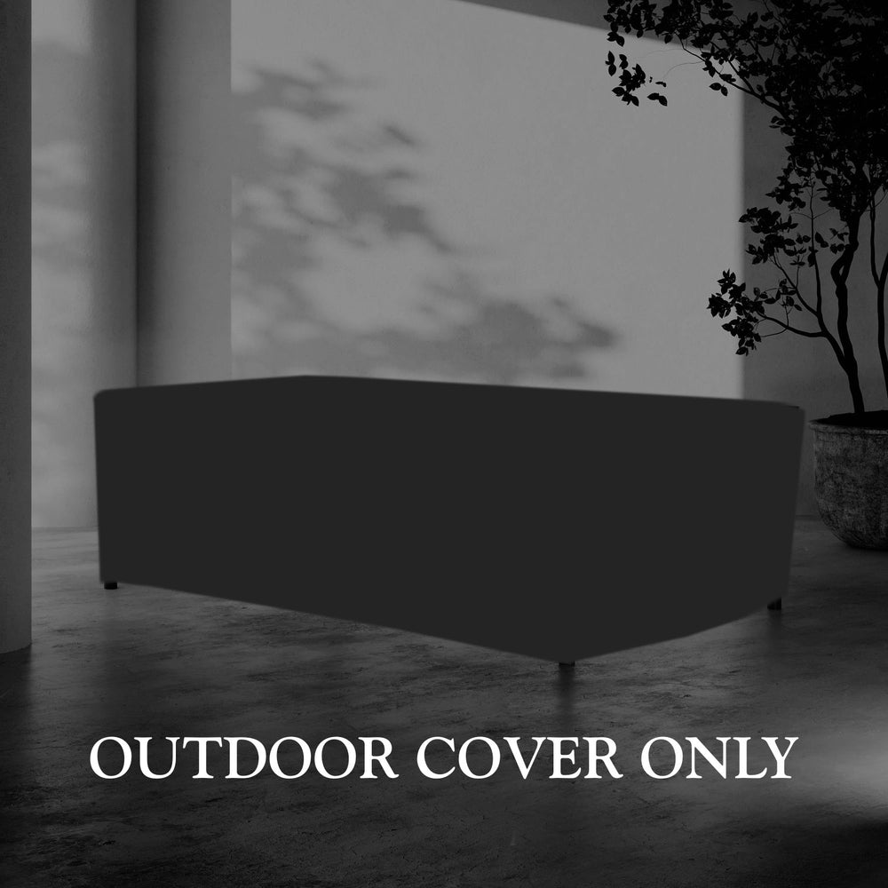 Lemieux et Cie Hudson Outdoor Cover for 84" dining table, dark rectangular protective cover on stone floor beside potted tree in soft daylight.