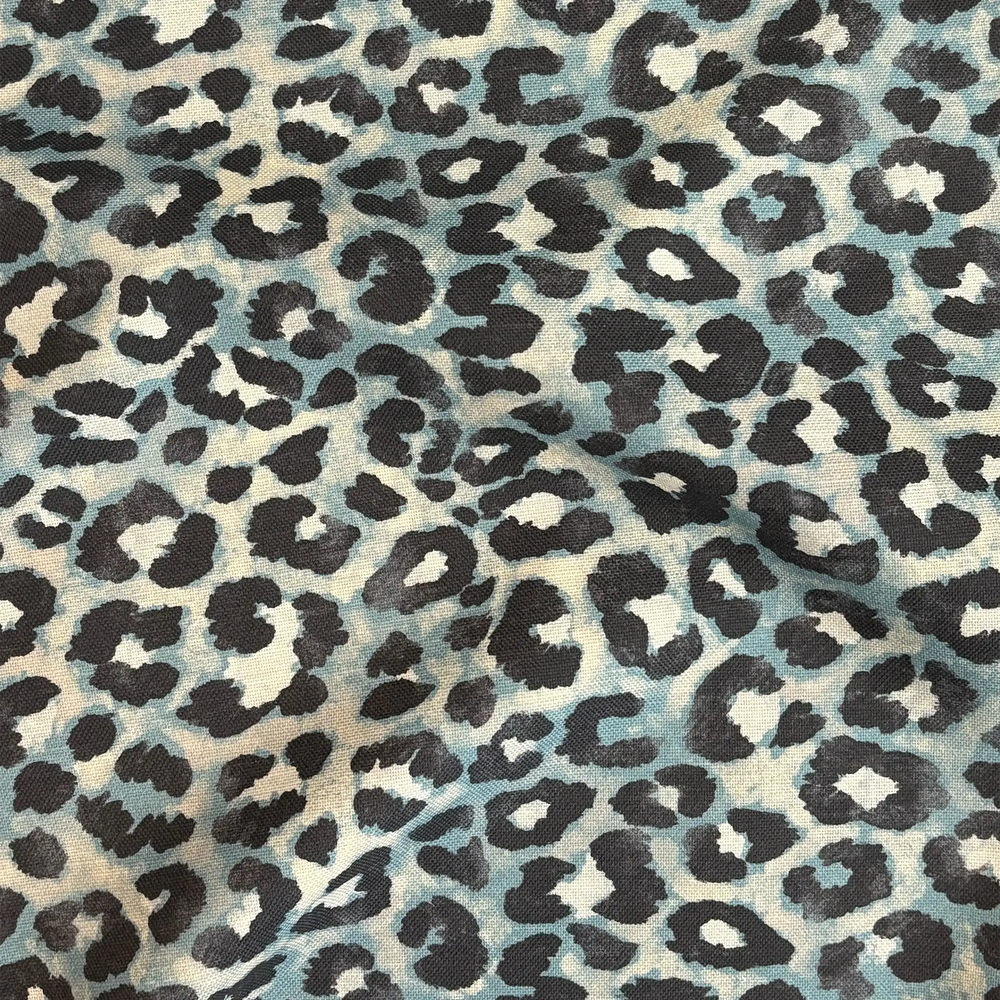 Lemieux et Cie Outdoor Pillow in Teal Leopard, charcoal and blue leopard print pattern on neutral ground, close detail of draped textile surface.