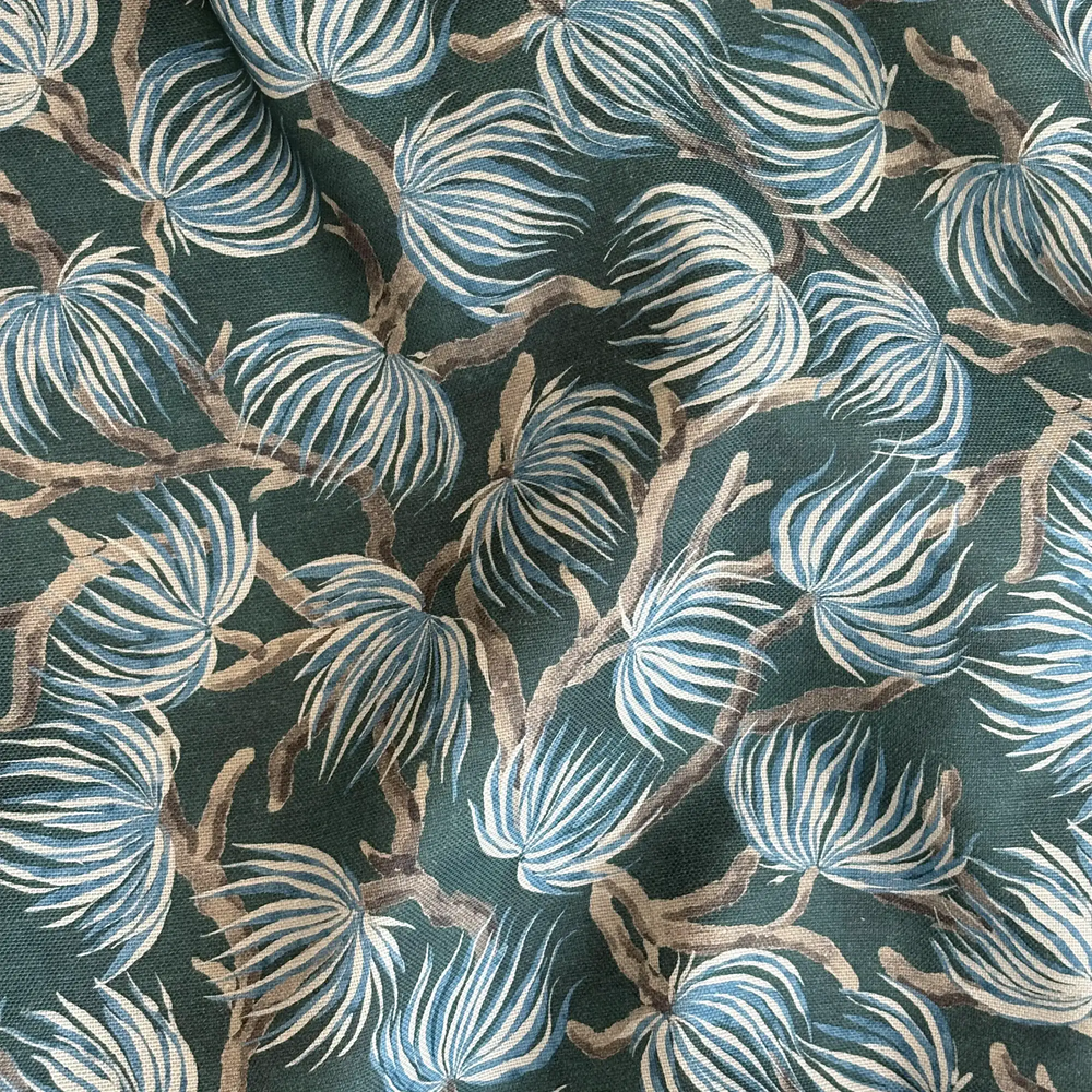 Lemieux et Cie Winding Palm Plant outdoor pillow in teal with blue and taupe botanical motif, woven textile detail shot showing organic palm frond pattern.