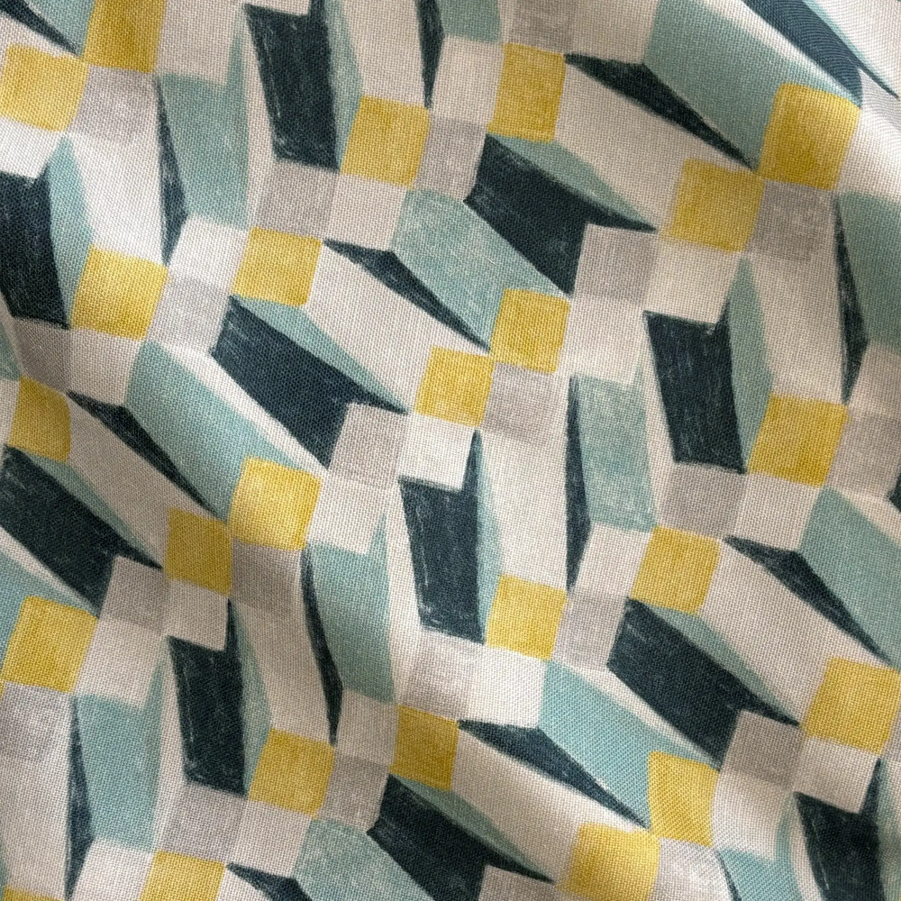Lemieux et Cie Op Art Blue outdoor pillow in abstract geometric pattern with yellow, sage, charcoal and ivory, woven textile detail shown in soft natural light.