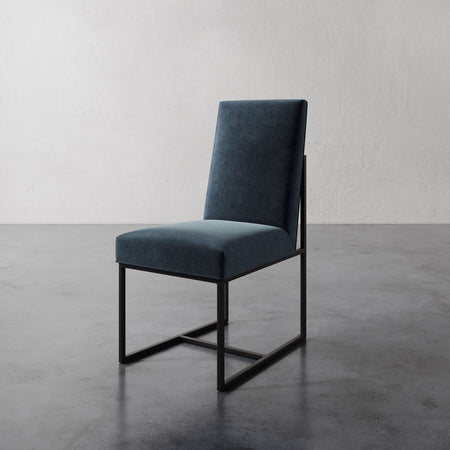 Lemieux et Cie Dupont Dining Side Chair in deep teal upholstery with structured frame, shown on polished concrete floor against white plaster wall.