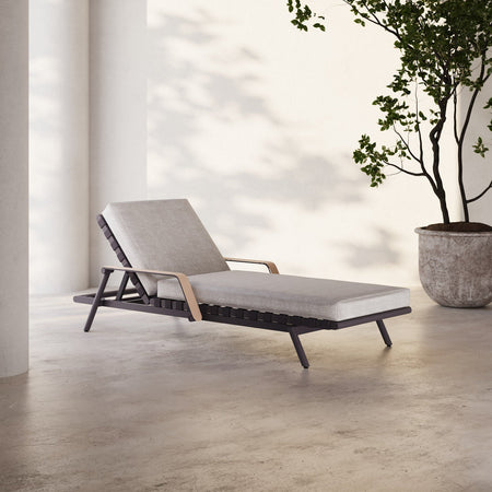 Lemieux et Cie Hudson Chaise Lounge with adjustable back and warm-toned arms, chaise lounge on stone floor in bright daylight with potted tree beside white walls.