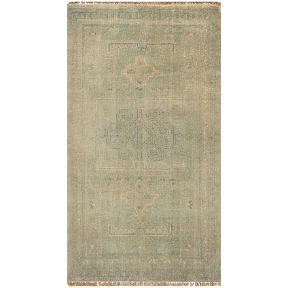 Lemieux et Cie Kouang rug in sage and blush hand-knotted wool with faded geometric motifs, shown on white studio backdrop with visible fringe.