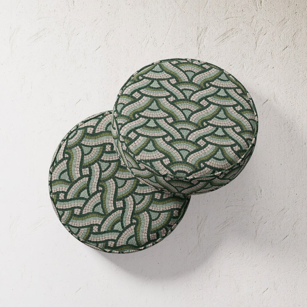 Lemieux et Cie Outdoor Pillow in green and cream mosaic pattern, two round cushions stacked on textured white plaster wall.
