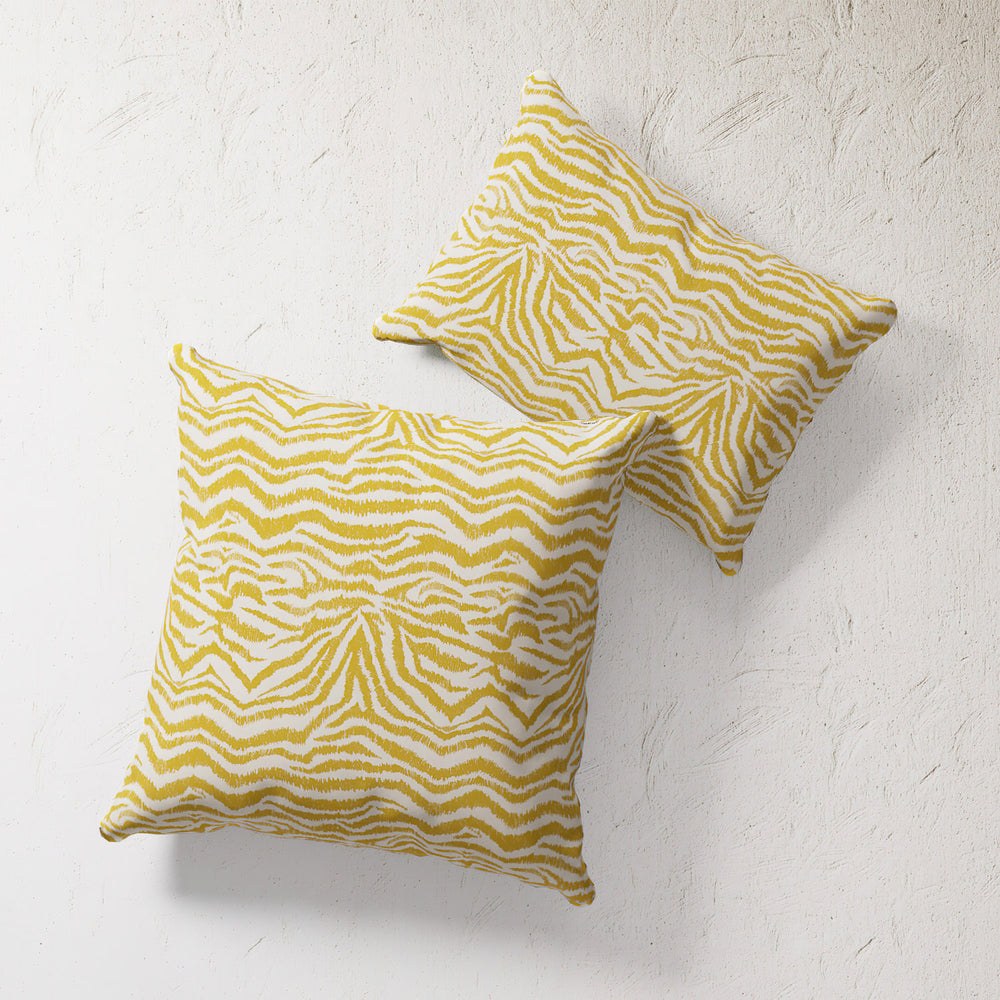 Lemieux et Cie Outdoor Pillow in Citron Zebra, two square pillows with organic yellow and ivory zebra striping, shown on textured white plaster wall.
