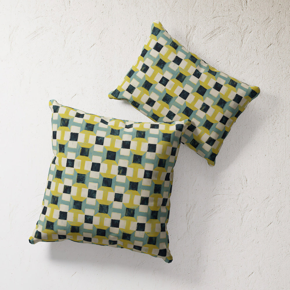 Lemieux et Cie Outdoor Pillow in Geometric Navy and Citron, abstract geometric pattern, two pillows on textured plaster backdrop.