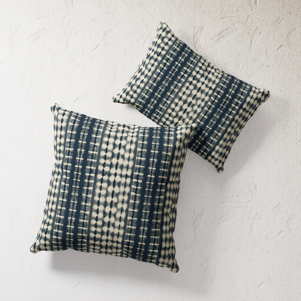 Lemieux et Cie Outdoor Pillow in indigo shibori pattern, two decorative pillows shown against textured plaster wall in soft light.