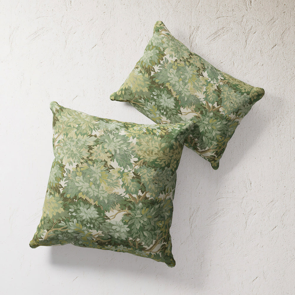 Lemieux et Cie Outdoor Pillow in Foliage Tapestry print, green botanical pattern on double-sided cushions against textured plaster wall.