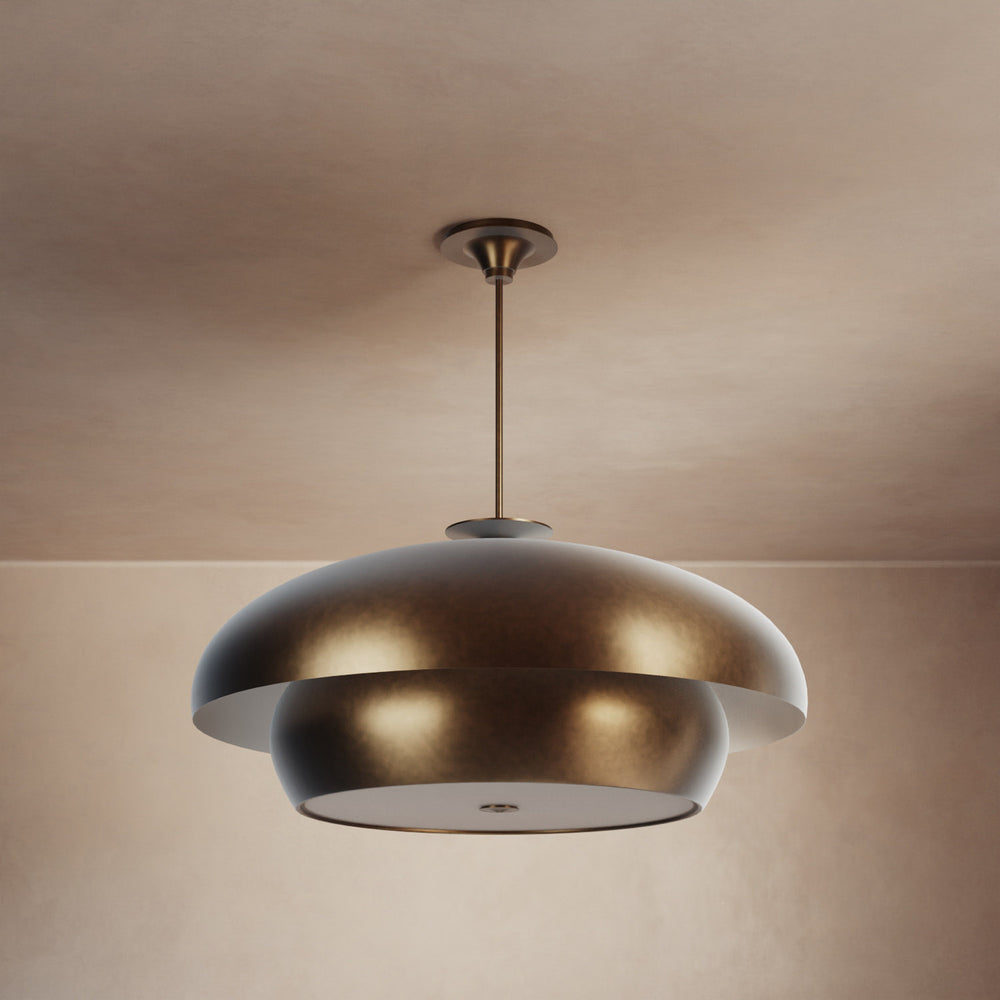 Lemieux et Cie Solene Chandelier, tiered dome pendant in warm patinated finish, suspended from slim rod in neutral plaster-walled room with soft ambient light.