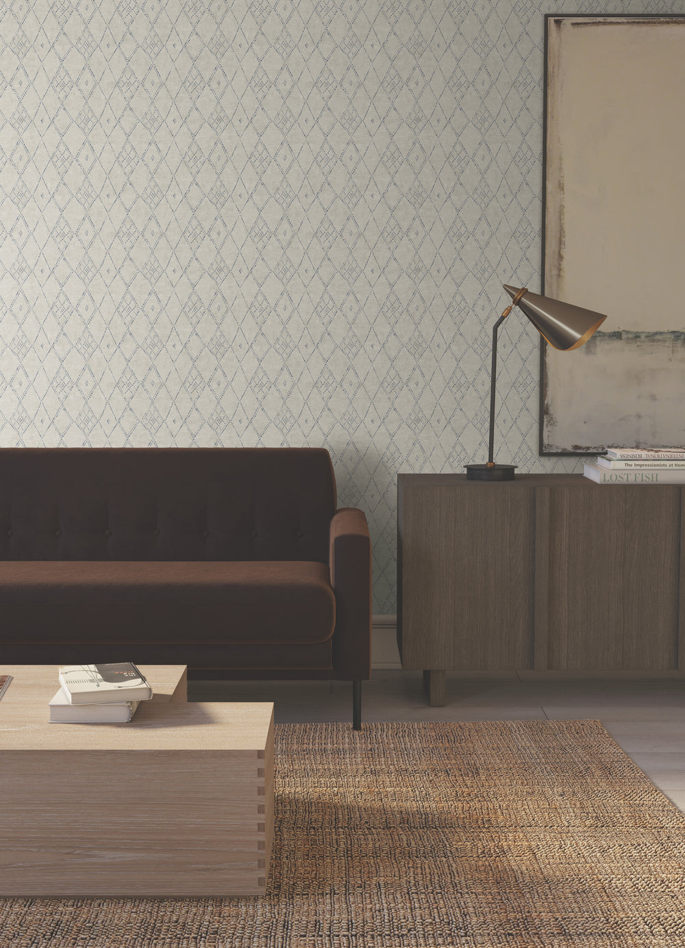 Lemieux et Cie Souk Diamonds wallpaper in taupe brown and denim blue, handpainted diamond pattern, styled in sitting room with dark sofa and woven rug.