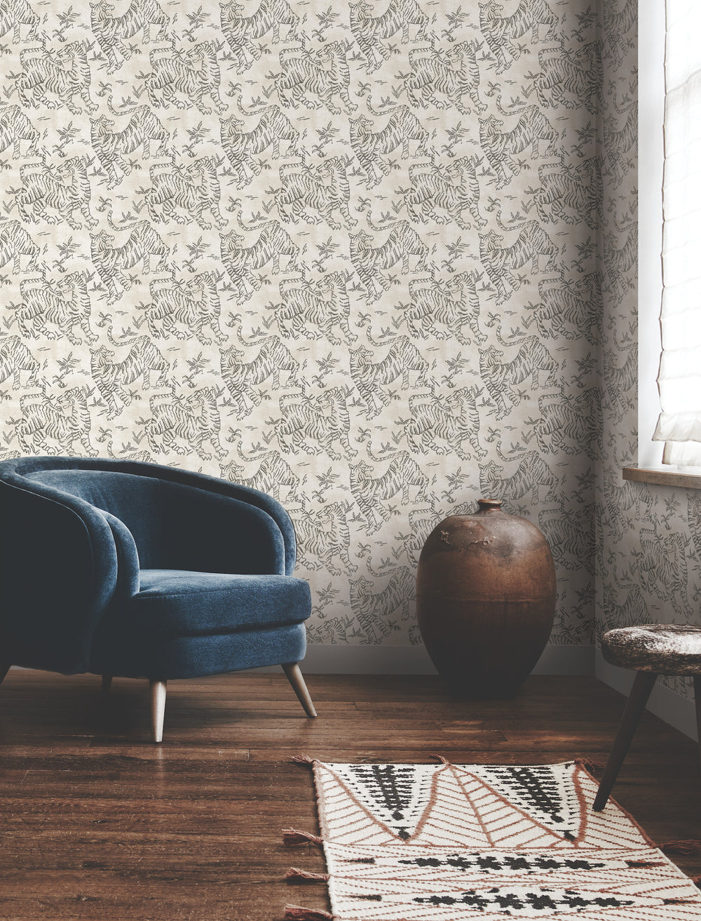 Lemieux et Cie Orly Tigers wallpaper in charcoal gray on taupe brown, shown in sitting room with wood floors and blue chair.