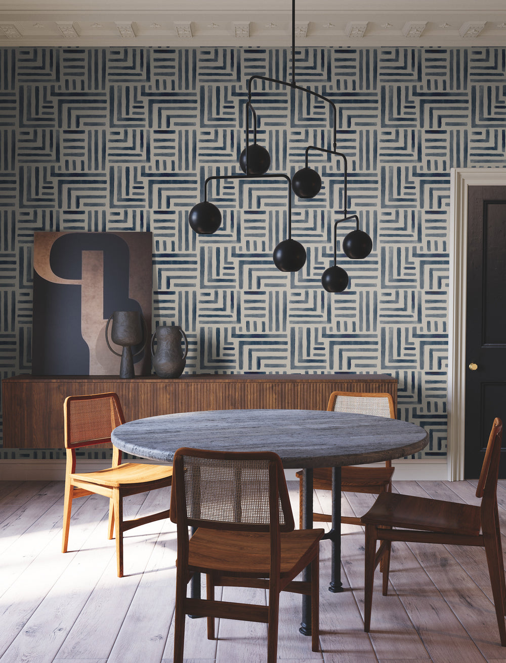 Lemieux et Cie Painterly Labyrinth wallpaper in blue and cream geometric maze pattern, dining room with round table, caned chairs, dark chandelier, light wood floors