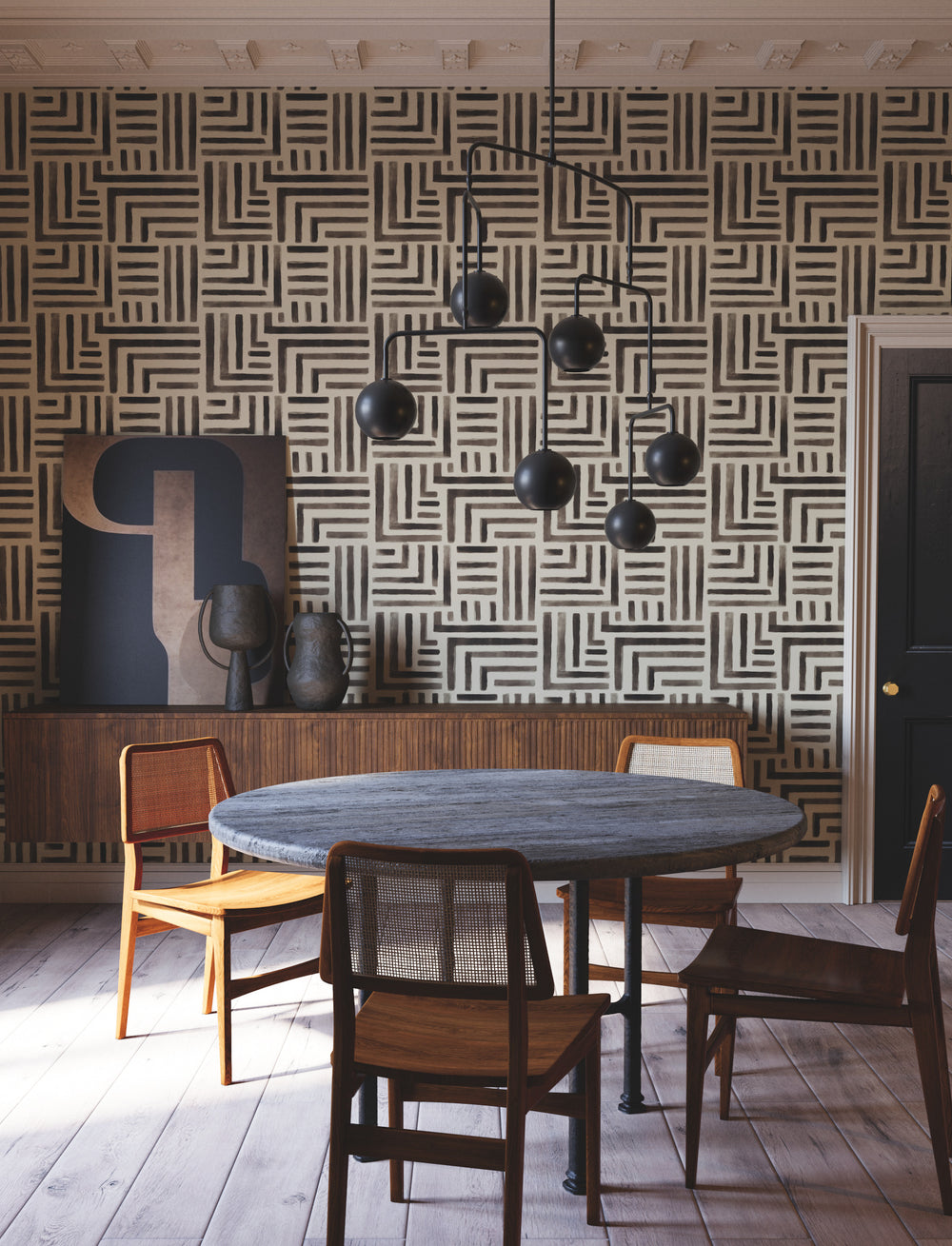 Lemieux et Cie Painterly Labyrinth wallcovering in dark gray and beige geometric pattern, shown in a dining room with wood floors and sculptural chandelier.