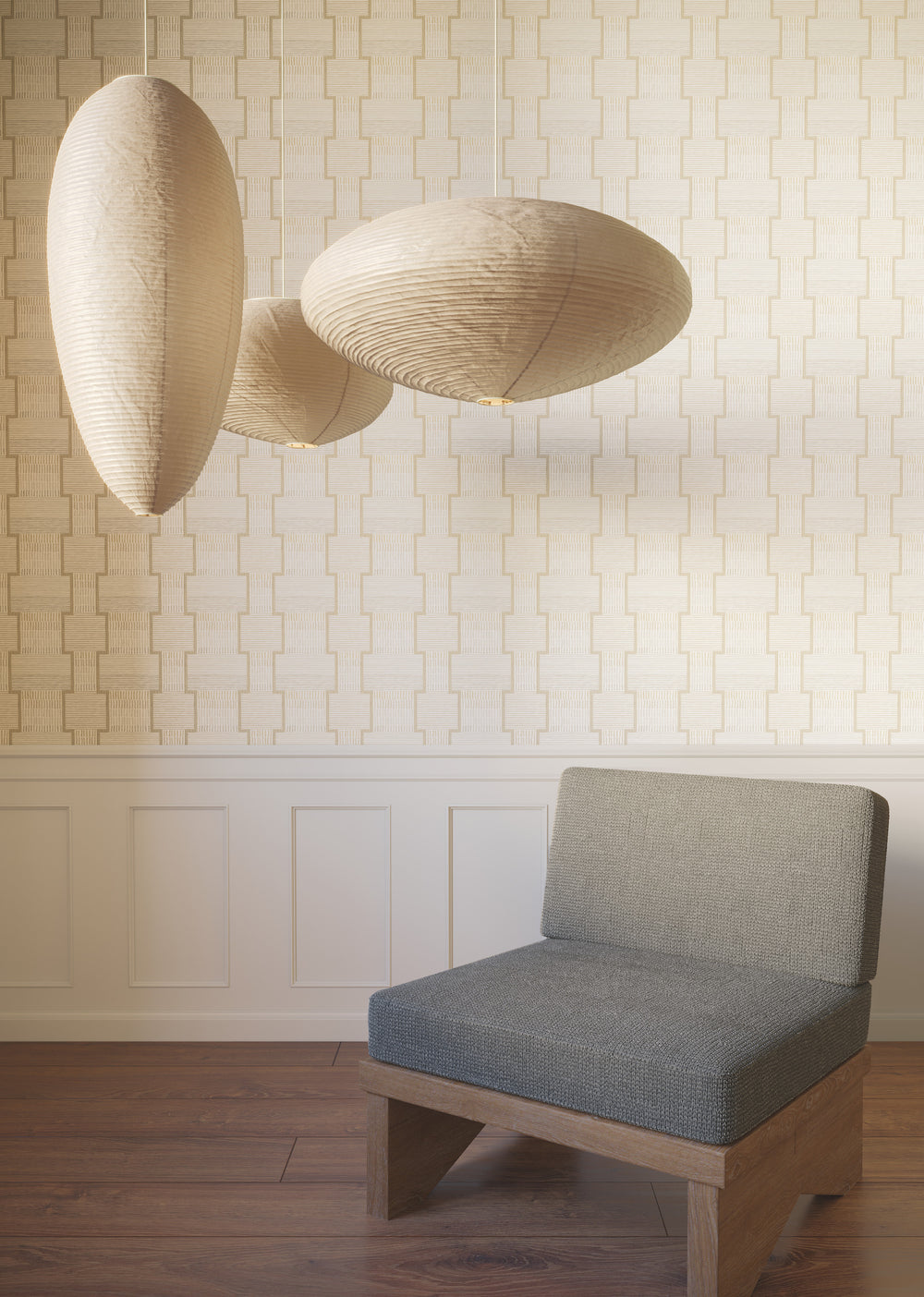Lemieux et Cie La Broderie in fawn beige and dove gray, pendant lights with organic sculptural shades, hung above a gray upholstered chair in a room with geometric wallpaper and wood floors.