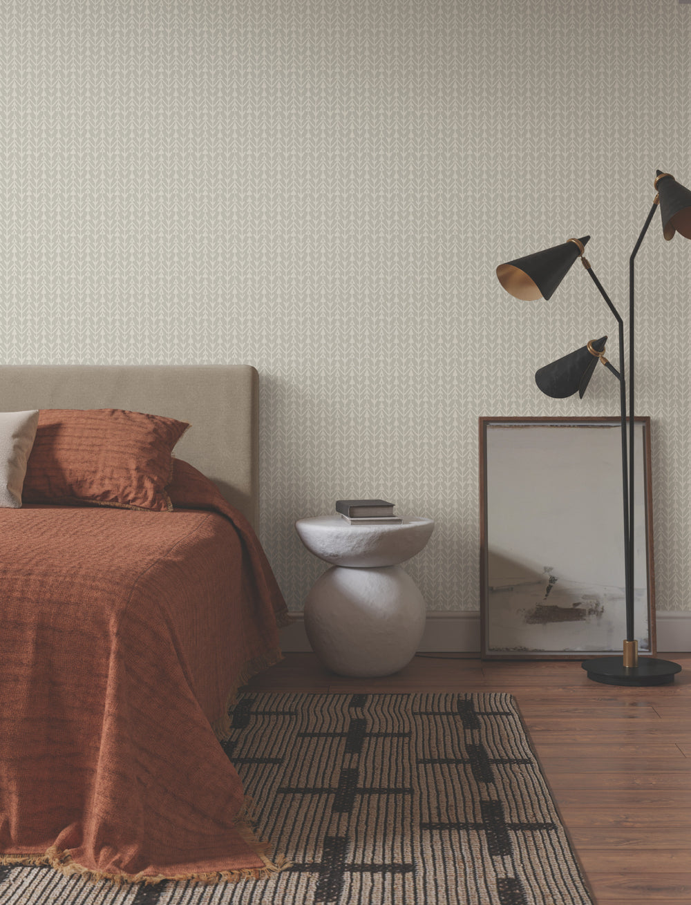 Lemieux et Cie Martigue Stripe in black olive, woven stripe rug placed bedside on wood floors against patterned wallcovering in a warm-toned bedroom.