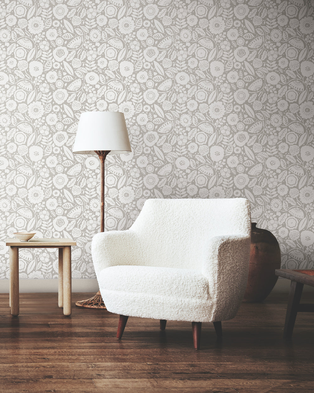 Lemieux et Cie Camelia Blossom wallpaper in white dove and cloud gray, seated beside ivory bouclé chair and table lamp on wood floors.