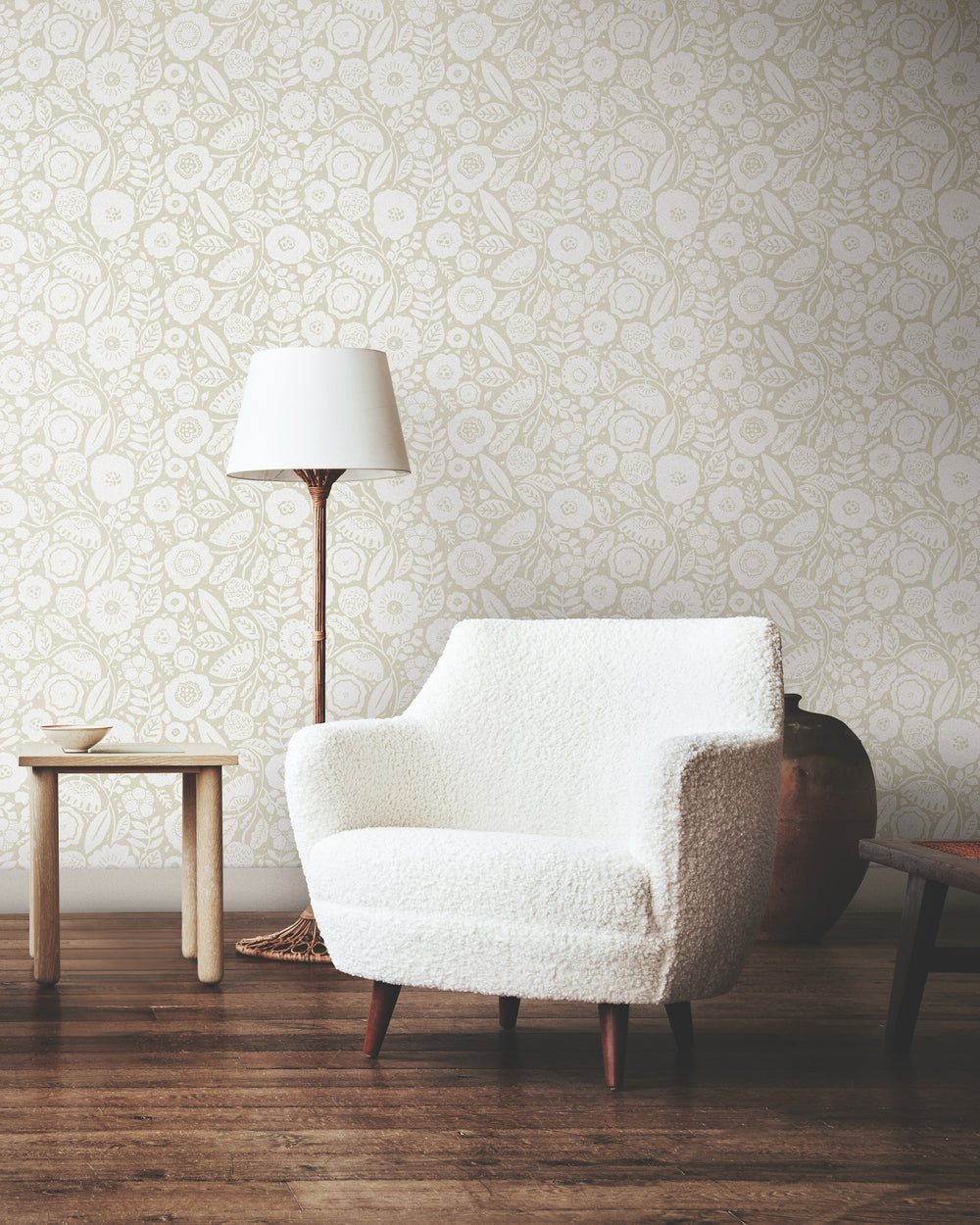 Lemieux et Cie Camelia Blossom wallpaper in chantilly white and beige linen, shown in sitting room with textured white chair, wood floors, and warm light.